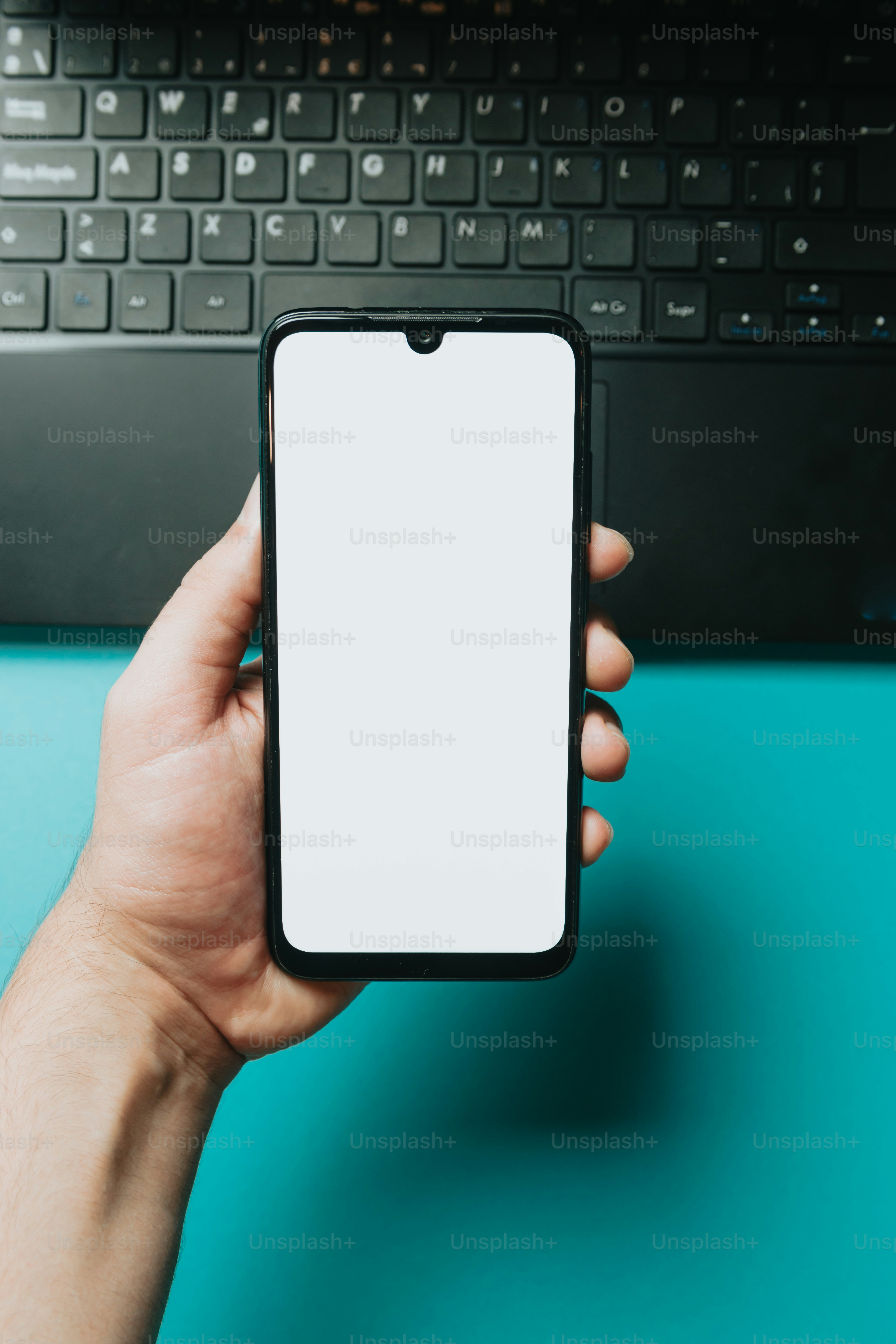 a person holding a cell phone in front of a laptop